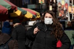 A woman, who declined to give her name, wears a mask, Jan. 30, 2020, in New York. She works for a pharmaceutical company and said she wears the mask out of concern for the coronavirus.