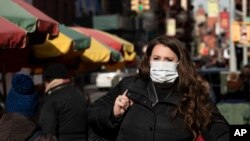 A woman who declined to give her name wears a mask, Jan. 30, 2020, in New York. She works for a pharmaceutical company and said she was concerned about coronavirus infection. "I'd wear a mask if I were you," she said. 