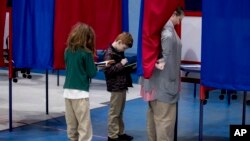 Samantha Murch acopañada por sus dos hijos, Alexander, de 8 años, y Jacob, de 11, vota en la primaria demócrata de New Hampshire en ishop O'Neill Youth Center, el martes, 11 de febrero de 2020 en Manchester, New Hampshire.