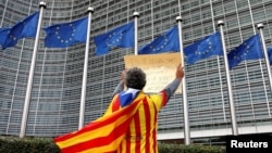 Catalan Raimon Castellvi wears a flag with an Estelada (Catalan separatist flag) as he protests outside the European Commission in Brussels after Sunday's independence referendum in Catalonia, Belgium, Oct. 2, 2017. 