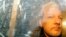 FILE - In this May 1, 2019 file photo, buildings are reflected in the window as WikiLeaks founder Julian Assange is taken from court, where he appeared on charges of jumping British bail seven years ago, in London. 