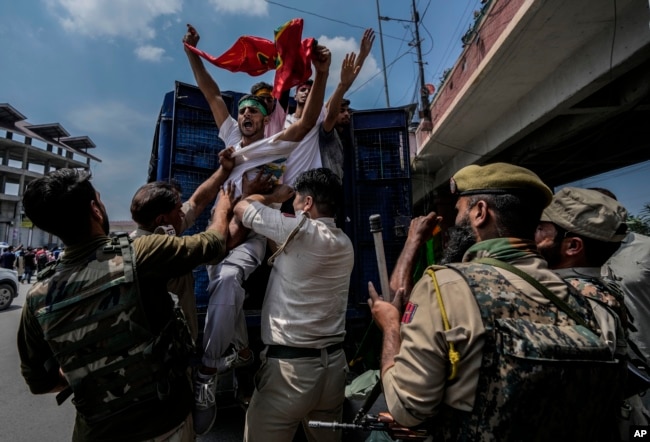 Indian policemen detain Kashmiri Shiite Muslims for participating in a religious procession during restrictions in Srinagar, Indian controlled Kashmir, Sunday, Aug. 7, 2022. Authorities had imposed restrictions in parts of Srinagar, the region's main city, to prevent gatherings marking Muharram from developing into anti-India protests. (AP Photo/Mukhtar Khan)