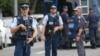 Armed police keep watch as people pay their respects in front of floral tributes for victims of the March 15 mosque attacks, in Christchurch, March 16, 2019.