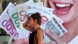 A woman walks by a pawn shop in central Athens, Greece.