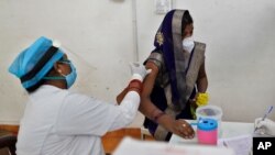 A woman receives the AstraZeneca vaccine for COVID-19 at a hospital in Prayagraj, India. Saturday, May 1, 2021. In hopes of taming a monstrous spike in COVID-19 infections, India opened vaccinations to all adults Saturday, launching a huge…