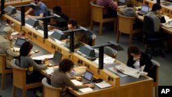 FILE - People work on laptops in a reading room at the British Library in London, June 20, 2011. 