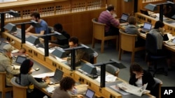 FILE - People work on laptops in a reading room at the British Library in London, June 20, 2011. 