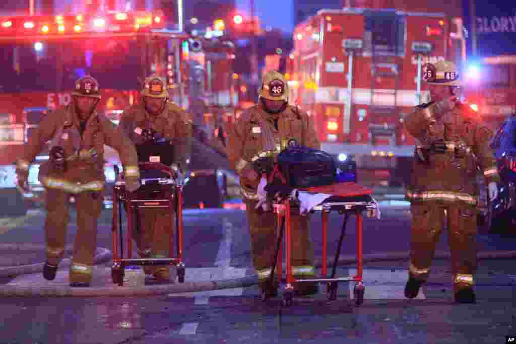 Los Angeles Fire Department firefighters push ambulance stretchers at the scene of a structure fire that injured multiple firefighters, according to a fire department spokesman, May 16, 2020, in Los Angeles, California.