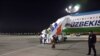 People disembark from a plane upon their arrival from Syria at an airport in Tashkent, Uzbekistan, April 30, 2021. Uzbekistan brought home women and children from Syria where they had been staying at camps with other families of Islamic State fighters.