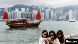 FILE - Tourists take photos in front of Victoria Harbour, in Tsim Sha Tsui, in Hong Kong, China April 29, 2024.