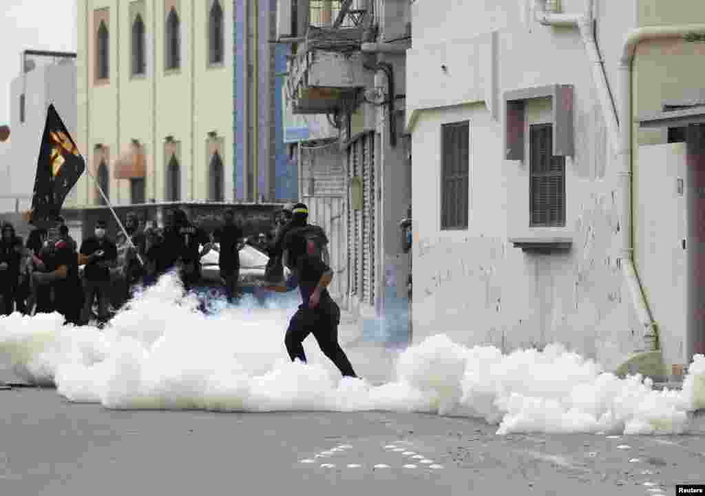 An anti-government protester throws a stone at riot police amid teargas fired by the police during clashes in the village of Diraz, west of Manama, Bahrain. Protests following the death of 20-year-old Fadhel Abbas threatened to sour a new attempt to restart negotiations between Bahrain&#39;s government, led by the ruling al-Khalifa family, and opposition groups.