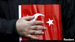 FILE - A supporter of Gulen movement holds a Turkey's national flag during a protest outside the Kanalturk and Bugun TV building in Istanbul, Turkey, Oct. 28, 2015. 