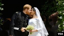 FILE - Prince Harry and Meghan Markle kiss on the steps of St George's Chapel in Windsor Castle after their wedding in Windsor, near London, England, Saturday, May 19, 2018. (Ben Birchhall/pool photo via AP)