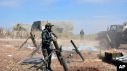 FILE - In this photo released by the Syrian official news agency SANA, Syrian army soldiers prepare to launch a mortar towards insurgents in the village of Kfar Nabuda, in the countryside of Hama province, Syria, May 11, 2019.