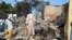 FILE - Residents watch as two men walk amidst rubble after Boko Haram militants raided the town of Benisheik, west of Borno State capital Maiduguri, Nigeria, Sept. 19, 2013.
