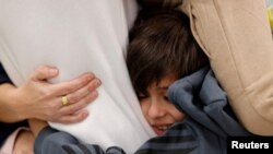 FILE —Yuval Brodutch, 8, cuddles his father Avihai Brodutch shortly after they were reunited in Israel on November 26, following the arrival of Avihai's wife Hagar and children Oria Brodutch, 4, Yuval Brodutch, 8, and Ofri Brodutch, 10, in Israel on November 27, 2023.