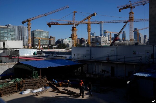 Workers labor near a construction site with cranes near the central business district skyline in Beijing, China, Monday, Oct. 11, 2021. (AP Photo/Ng Han Guan)