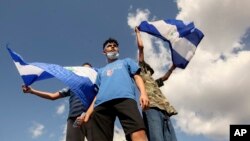 Young men wave national flags during a protest demanding the government release hundreds of protesters held in custody since 2018, in Managua, Nicaragua, March 16, 2019. 