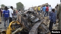 People look at damage in a market area after a bomb explosion in Ajilari-Gomari near the city's airport, Maiduguri, Borno State March 2, 2014.