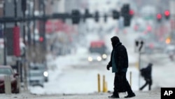 Seorang warga tampak menyeberang di jalanan yang diselimuti salju di pusat kota Kansas City, Missouri, di saat badai musim dingin melintasi wilayah tersebut pada 12 Februari 2025. (Foto: AP/Charlie Riedel)