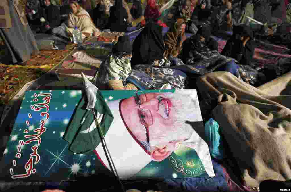 Supporters of Tahirul Qadri sit next to his poster as they wait for his arrival during a protest in Islamabad, Pakistan, January 14, 2013.