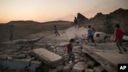 FILE - Children play on debris in a neighborhood retaken by Iraqi security forces during fighting against Islamic State militants in West Mosul, Iraq, June 25, 2017.