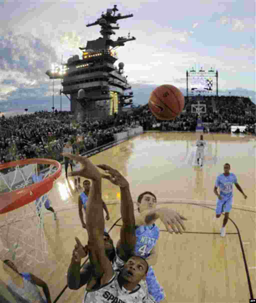 In this image taken with a fisheye lens, North Carolina forward Tyler Zeller (44) swats the rebound away from Michigan State center Adreian Payne, bottom, during the first half of the Carrier Classic NCAA college basketball game aboard the USS Carl Vinson