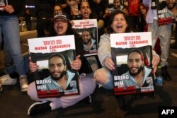 Relatives hold placards of Israeli hostages held in Gaza, during a rally calling for their release, in Tel Aviv on January 20, 2023. The placards show Matan Zangauker.