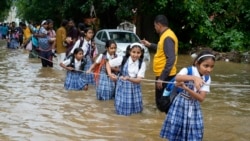 Students hold a rope as they cross a street flooded after heavy rains, on their way home in Ajmer, India.