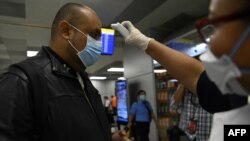 Un pasajero con mascarilla en el Aeropuerto Internacional de San Óscar Romero en San Luis Talpa, El Salvador, se somete al control de temperatura como precaución contra la propagación del nuevo coronavirus, el 12 de marzo de 2020.