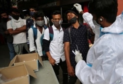 Un trabajador de la salud con traje protector recolecta una muestra de un hisopo nasal de un viajero para realizar una prueba de COVID-19 fuera de una estación de tren en Bangalore, India, el 16 de junio de 2021.