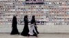 FILE - Shi'ite Muslim women walk past a wall with portraits of the deceased, who were killed in a bombing in a residential area in March 2013, during the Shi'ite Youm Ali procession in Karachi, Pakistan, June 27, 2016. 