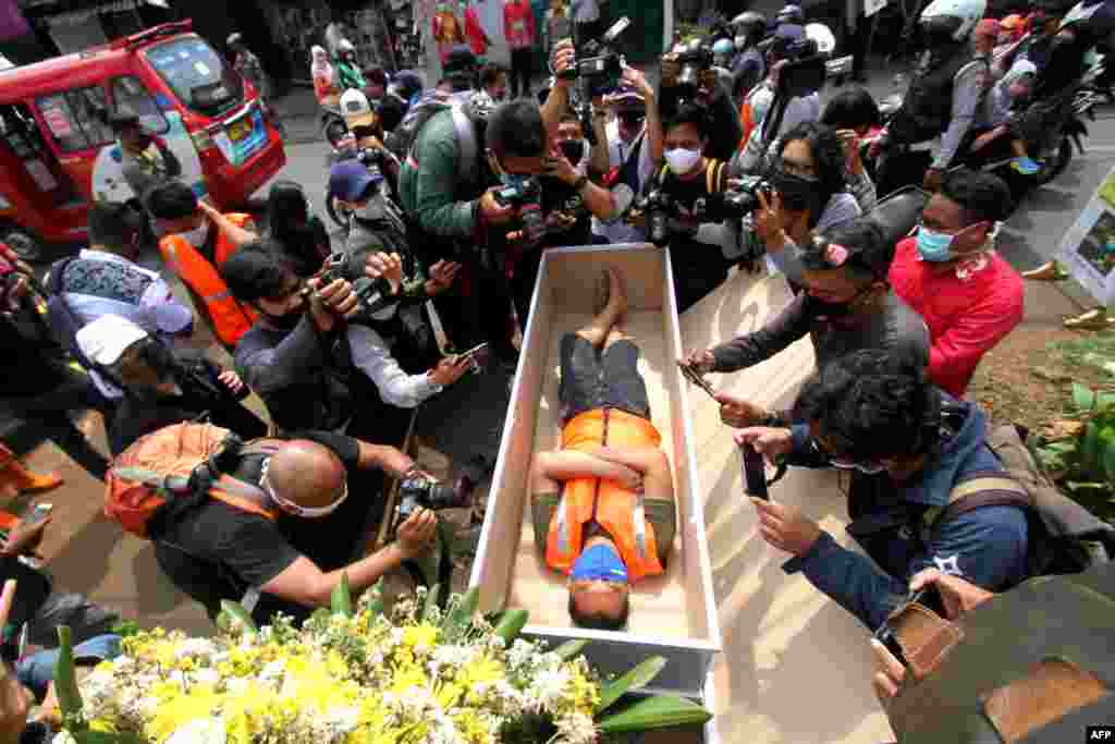 A man, who gets caught not wearing a face mask in public amid the COVID-19 pandemic, lies in a mock coffin as part of punishment by local authorities in Jakarta, Indonesia.