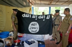 FILE - Police officers hold an Islamic State flag recovered during a raid in Ampara, Sri Lanka, April 28, 2019.