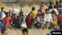 FILE - Syrian Kurds from Kobani walk to the border fences as seen from the Turkish border town of Suruc in Sanliurfa province, Turkey, June 26, 2015. 