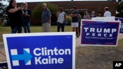 Early voters stand by campaign signs as they wait in line at a voting location in Dallas, Texas, Oct. 27, 2016.