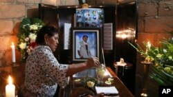 A woman dips a flower in a glass of water placed on the coffin of slain journalist Gumaro Perez during his wake in Acayucan, Veracruz state, Mexico, Dec. 20, 2017. 