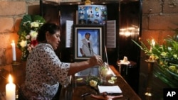 A woman dips a flower in a glass of water placed on the coffin of slain journalist Gumaro Perez during his wake inside his mother's home in Acayucan, Veracruz state, Mexico, Wednesday, Dec. 20, 2017. 