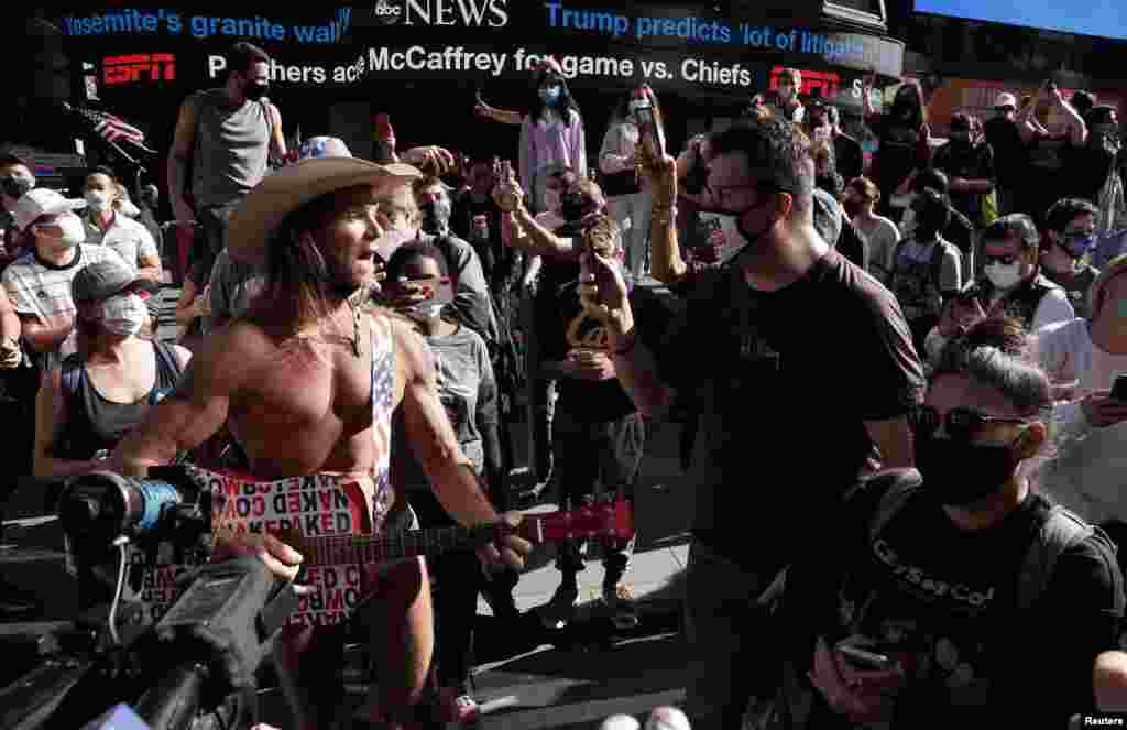 People react near the Naked Cowboy as media announce that Democratic U.S. presidential nominee Joe Biden has won the 2020 U.S. presidential election, on Times Square in New York City.