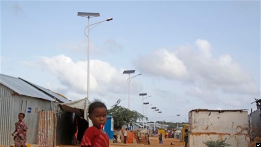 A Somali child stands under the solar powered lights at a refugee camp that were installed to help combat the rampant rapes that were occurring at night, in Mogadishu, Somalia, July 17, 2013.