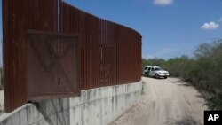 FILE - A U.S. Customs and Border Patrol vehicle passes along a section of border wall in Hidalgo, Texas, between the U.S. and Mexico, Aug. 11, 2017.