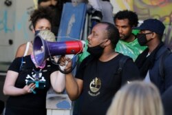 Mark Henry Jr., center, a Black Lives Matter leader, speaks into a megaphone in a doorway of the Seattle Police Department East Precinct building on June 11, 2020.