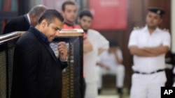 Canadian Al-Jazeera English journalist Mohammed Fahmy, left, listens during his retrial in a courtroom, in Tora prison, in Cairo, Egypt, June 25, 2015. 