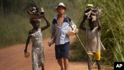 FILE - Children living in a cocoa-producing village walk back from the fields carrying wood and food stuffs on their heads on the outskirts of the town of Oume, Ivory Coast, June 30, 2005.