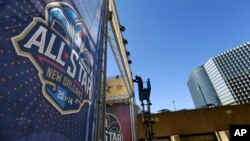 FILE - A worker attaches a banner to a scaffolding in New Orleans in preparation of the NBA All-Star basketball game, Feb. 13, 2014.