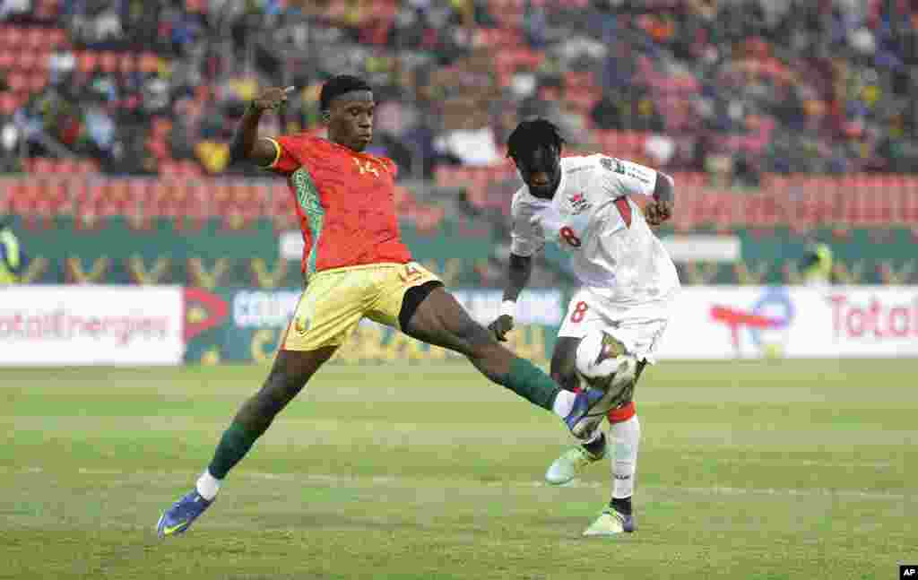 Guinea's Moriba Kourouma, left, is challenges by Gambia's Ebrima Darboe during the round of 16 match between Guinea and Gambia in Cameroon, Jan. 24, 2022.