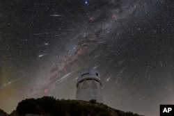 FILE - This Dec. 14, 2023 image made available by NOIRLab shows meteors from the Geminid meteor shower above the Nicholas U. Mayall Telescope at Kitt Peak National Observatory, a Program of NSF's NOIRLab, located about 90 kilometers southwest of Tucson. (NSF's NOIRLab via AP)