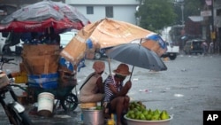 Los vendedores ambulantes se protegen de la lluvia de la tormenta tropical Laura en Puerto Príncipe, Haití, el domingo 23 de agosto de 2020. 