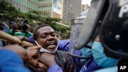 Kenyan policemen grab a protester by the throat as they detain him at a demonstration in downtown Nairobi, Kenya, July 7, 2020.
