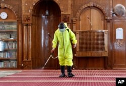 A Gaza municipality worker wearing protective gear sprays disinfectant as a precaution against the coronavirus, inside Beach Mosque in Gaza City, May 21, 2020.